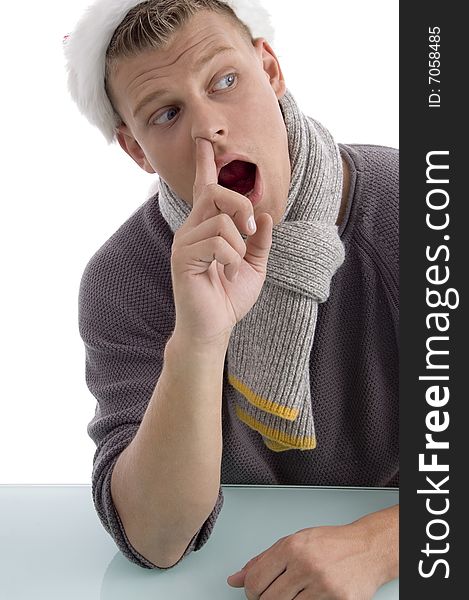 Young male with Christmas hat putting finger in his nose against white background