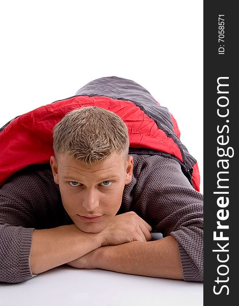 Young man covered himself with red sleeping bag against white background