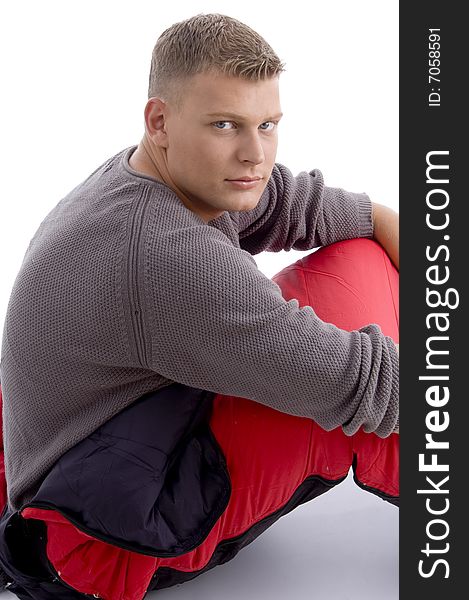 Young caucasian man sitting in the sleeping bag on an isolated background