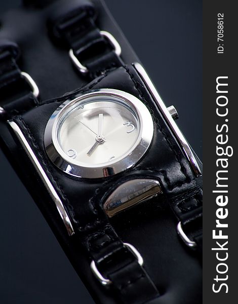 Little wristwatch with black strap on dark background