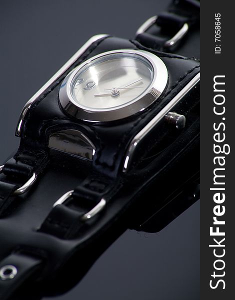 Little wristwatch with black strap on dark background