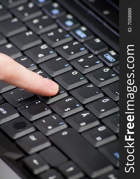 Black computer keyboard with black buttons with finger
