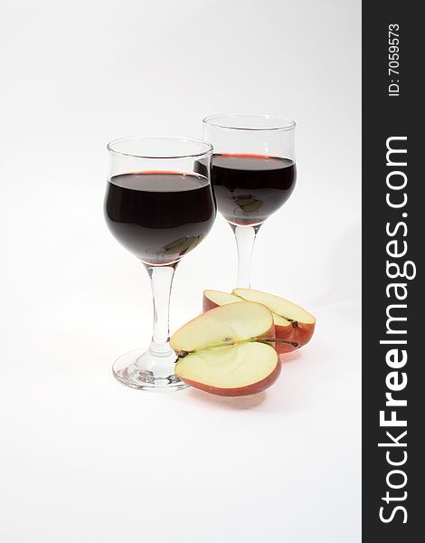 Isolated two goblets of red wine and slit apple. Isolated two goblets of red wine and slit apple
