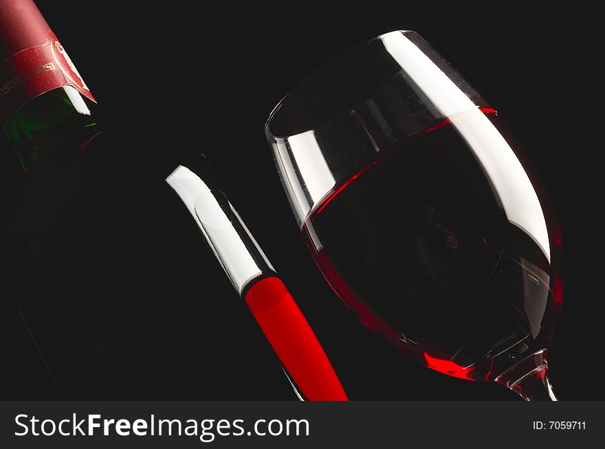 Glass and bottle of red wine on black