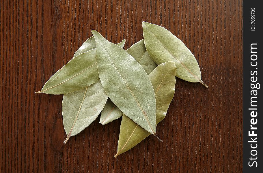 A small group of dry bay leaves on a wood background