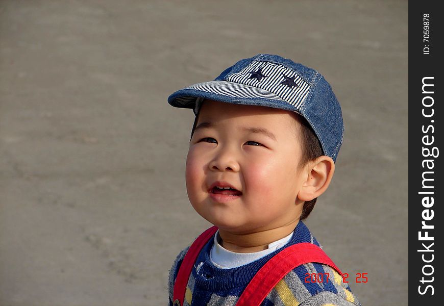 A cute chinese boy staning still and looking for kites flying in the sky in a sunny day. A cute chinese boy staning still and looking for kites flying in the sky in a sunny day