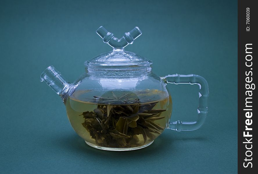 Teapot with tea close-up isolated on blue background