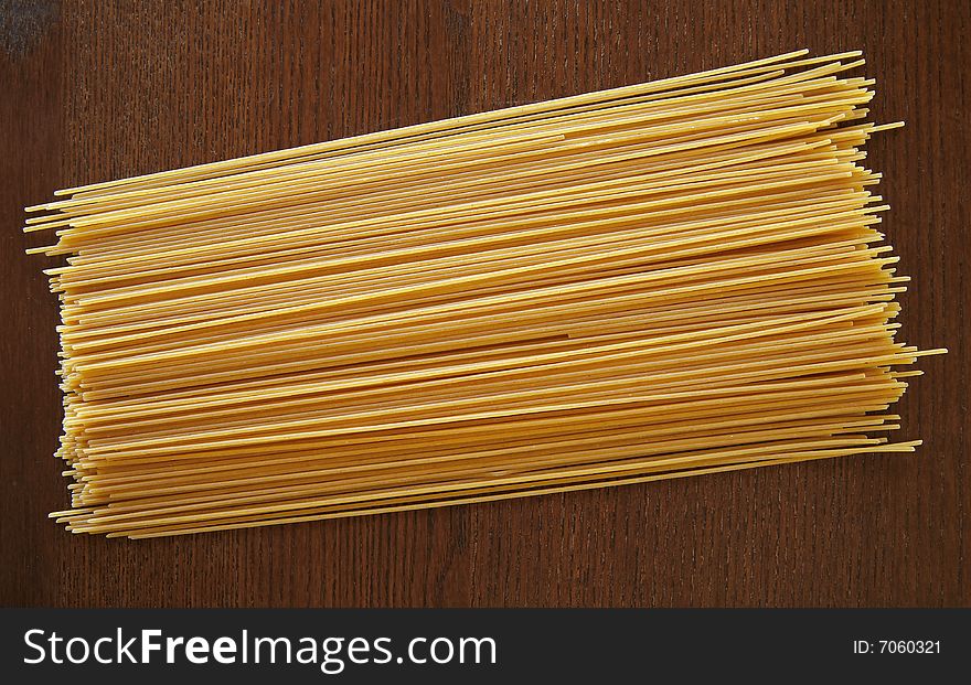 A pile of dried spaghetti noodles on a wood background. A pile of dried spaghetti noodles on a wood background