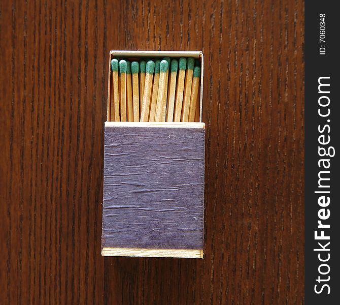 A small matchbox filled with wooden matches on a wood background