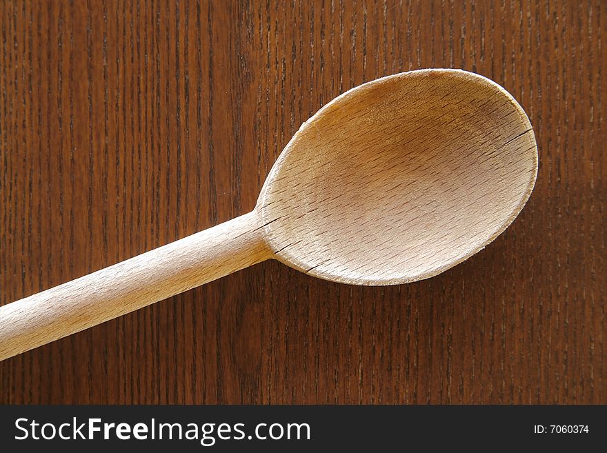 Detail of a wooden spoon on a wood background