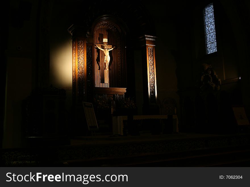 Sunlight streaming through a church window upon the crucified Christ. Sunlight streaming through a church window upon the crucified Christ