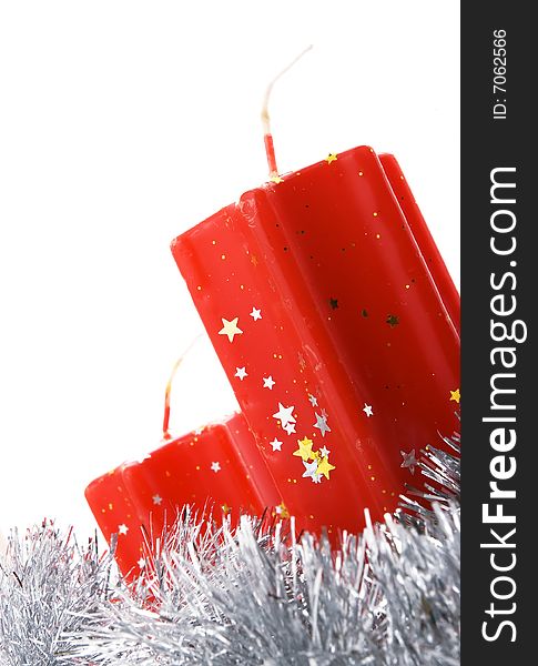 Two red candles decorated with stars and tinsel isolated over white