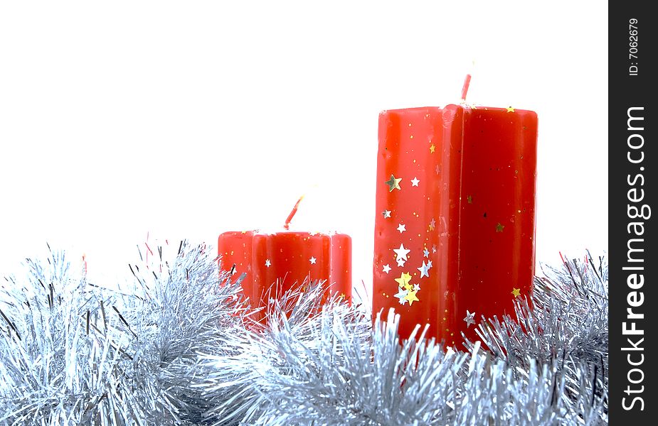 Two red candles decorated with stars and tinsel isolated over white