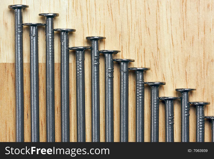 Declining Graph of Nails on a Wood Background.