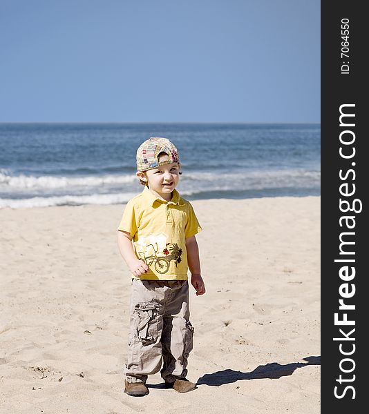 Little boy standing on the beach and smiling