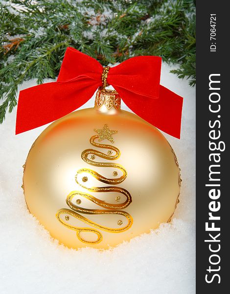 Christmas bauble with ribbon and branch on white snow