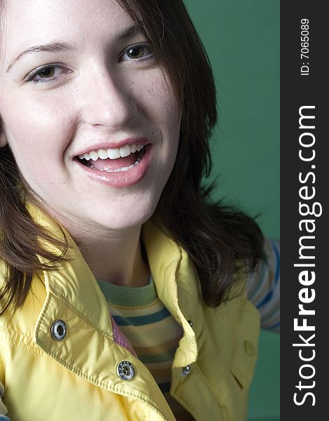 Young woman standing against a green background wearing a yellow vest. Young woman standing against a green background wearing a yellow vest