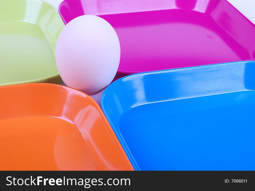 White egg among colorful plates. White egg among colorful plates