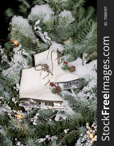 Miniature vintage ice skate ornaments hanging in tree with snow and lights. Miniature vintage ice skate ornaments hanging in tree with snow and lights