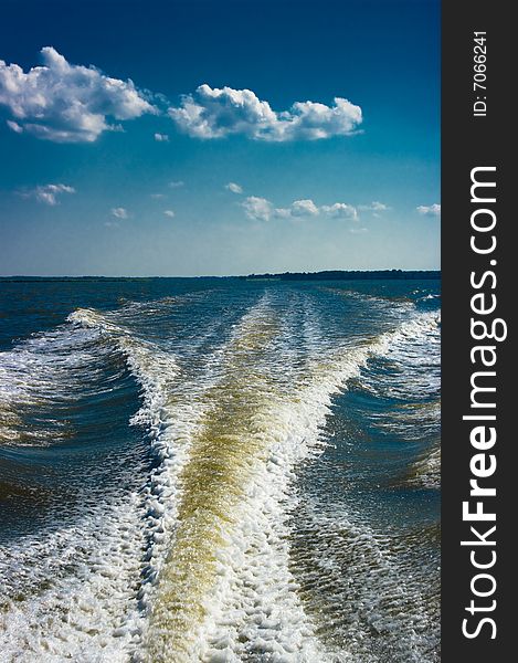 Wake of a speed boat against the blue sky