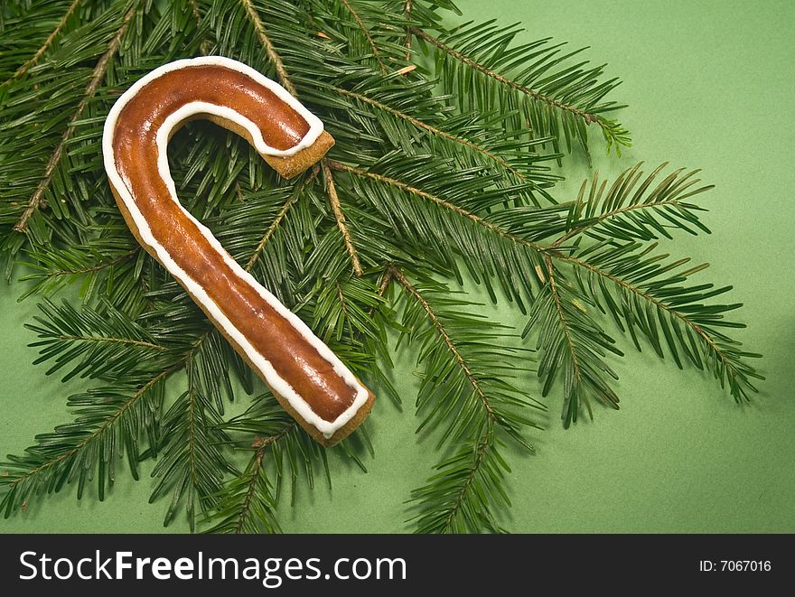 Candy cane cookie with fir branch isolated on green paper. Candy cane cookie with fir branch isolated on green paper