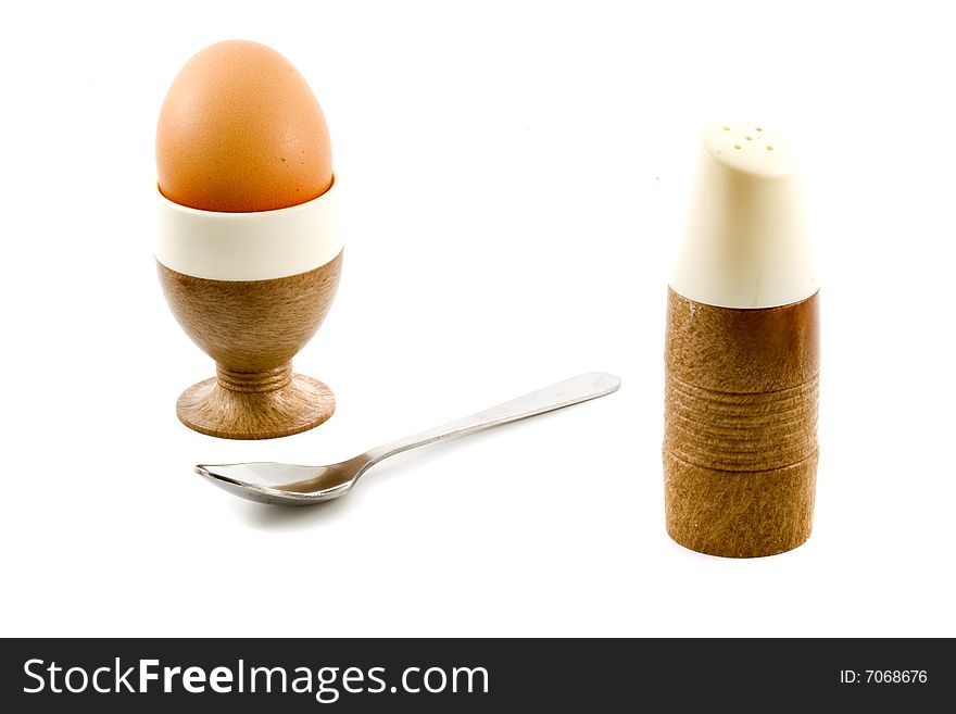 A soft boiled egg, a spoon and a saltpot