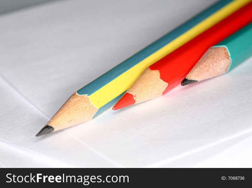 Closeup image of three pencils laying on white paper