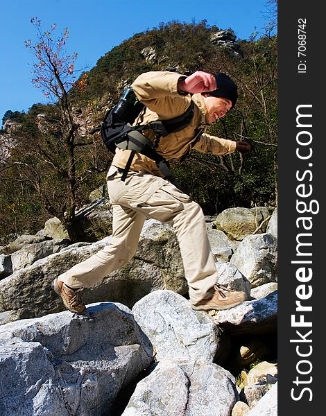 Hiker jumping from rock to rock while crossing river. Hiker jumping from rock to rock while crossing river.