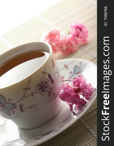 Cup Of Tea And Flowers Over Bamboo Mat