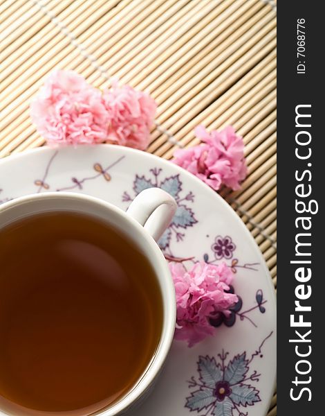 Cup of tea and flowers over bamboo mat
