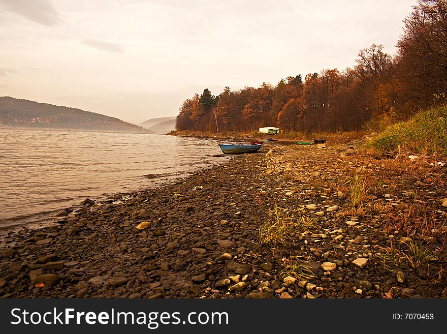 Autumn lake shore, boats, mountains