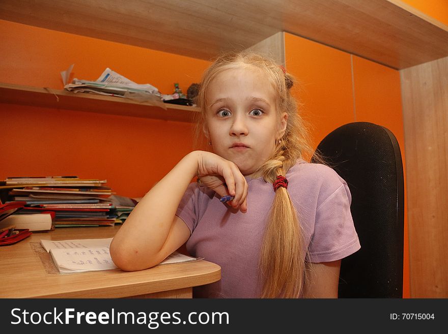 Young schoolgirl is sitting near the desk