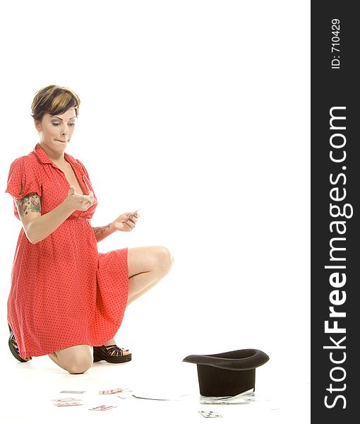 young actress with tattoos, a red girlish dress, poses different postures and expressions for an audition, with playing cards and a big black hat, over a white background. young actress with tattoos, a red girlish dress, poses different postures and expressions for an audition, with playing cards and a big black hat, over a white background