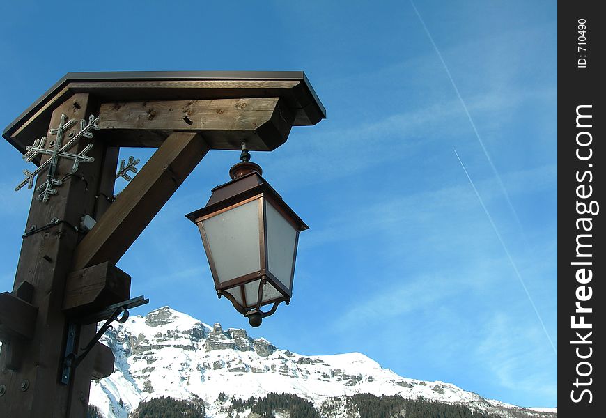 The snow covered mountains of La Contamins, in the french alps give a beautiful backdrop to this quaint street light. The snow covered mountains of La Contamins, in the french alps give a beautiful backdrop to this quaint street light
