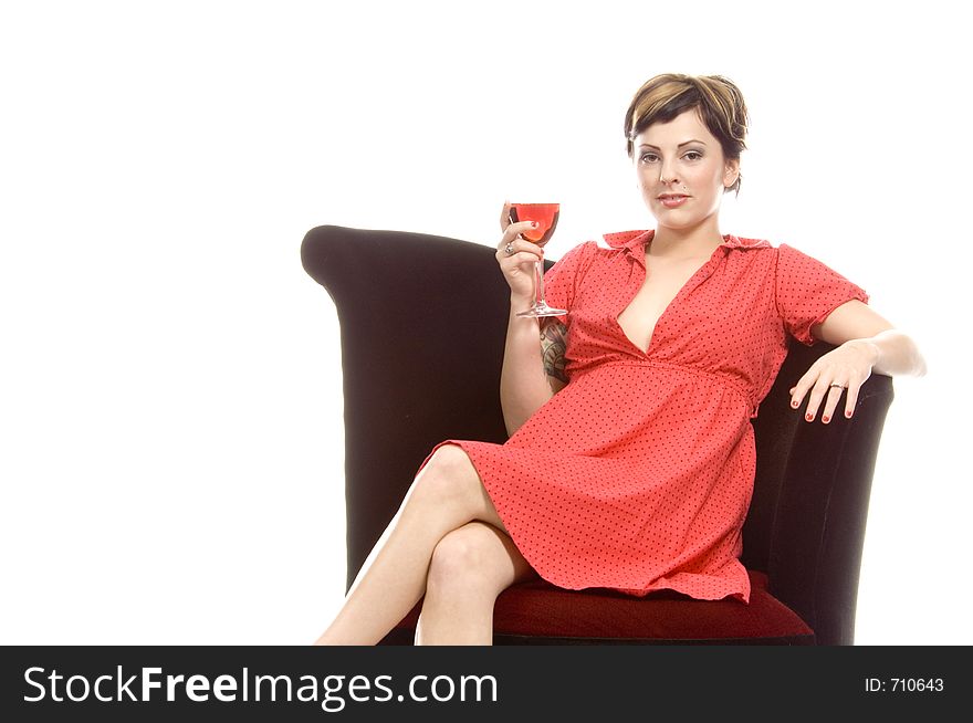 Young attractive actress sits on a black velvet chair in a studio and sips on a glass of sangria. Young attractive actress sits on a black velvet chair in a studio and sips on a glass of sangria