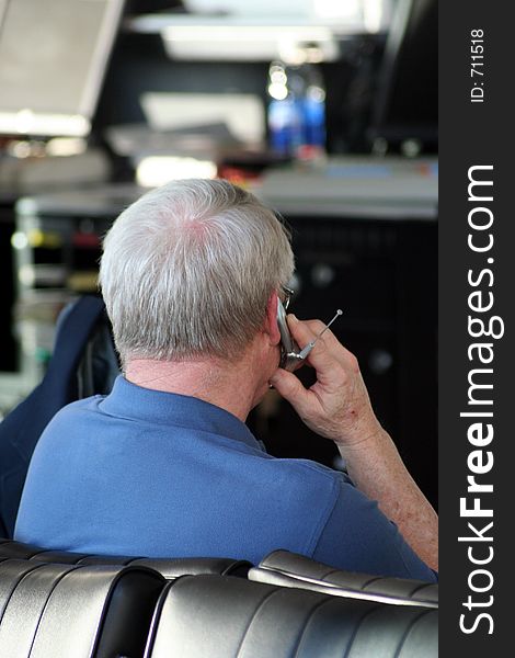 A senior male uses his cell phone to call while waiting for his airplane to board. A senior male uses his cell phone to call while waiting for his airplane to board