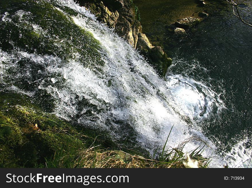 Small waterfall rushing over rock edge into a small lagoon. Small waterfall rushing over rock edge into a small lagoon.