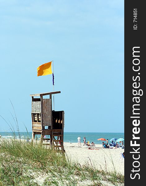 An empty lifeguard stand watches over the public visitors at an ocean beach. An empty lifeguard stand watches over the public visitors at an ocean beach