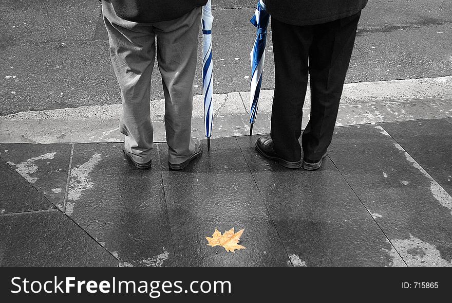 Image of two people with raincoats and a fallen leaf depicting cooler weather has arrived. Image of two people with raincoats and a fallen leaf depicting cooler weather has arrived