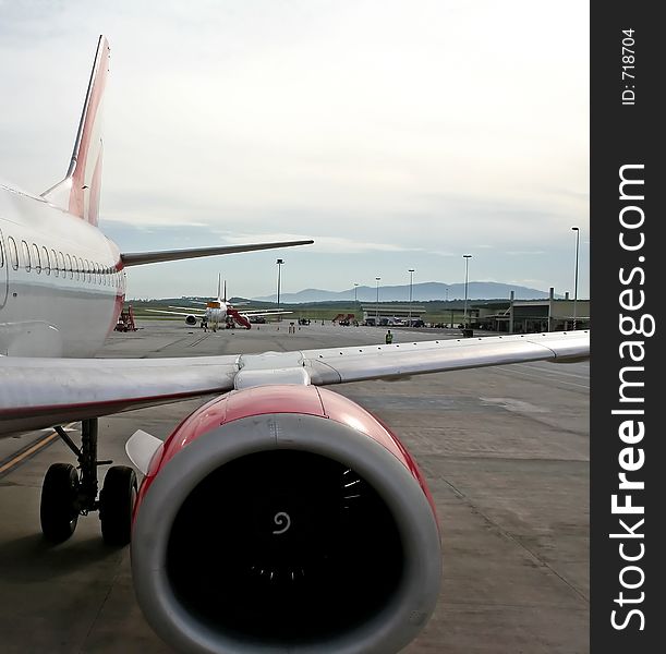 Detail of a wing and engine on an airplane parked on the runway of an airport. Detail of a wing and engine on an airplane parked on the runway of an airport