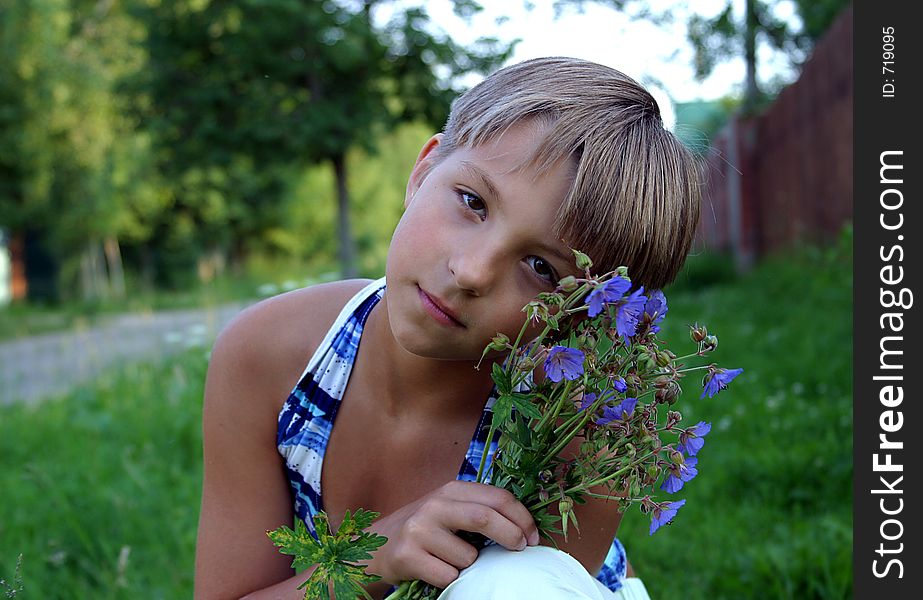 The girl sitting with a bouquet of field flowers. The girl sitting with a bouquet of field flowers.