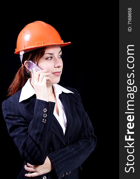 Girl in a business suit with phone and in a helmet on a black background. Girl in a business suit with phone and in a helmet on a black background