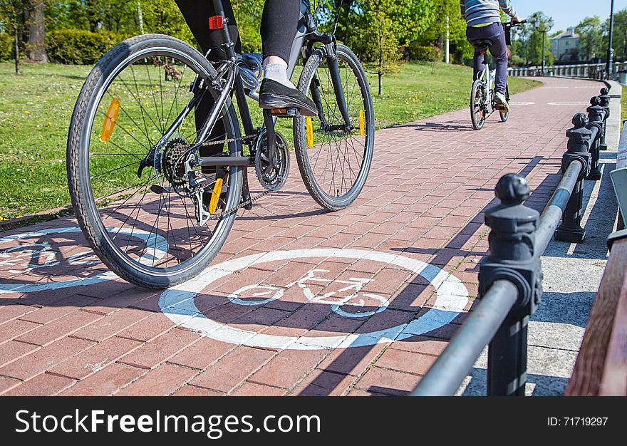 Two bicyclists riding on the bike path outside on spring day