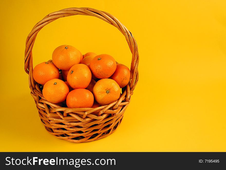 Basket of fresh oranges on yellow background. Basket of fresh oranges on yellow background