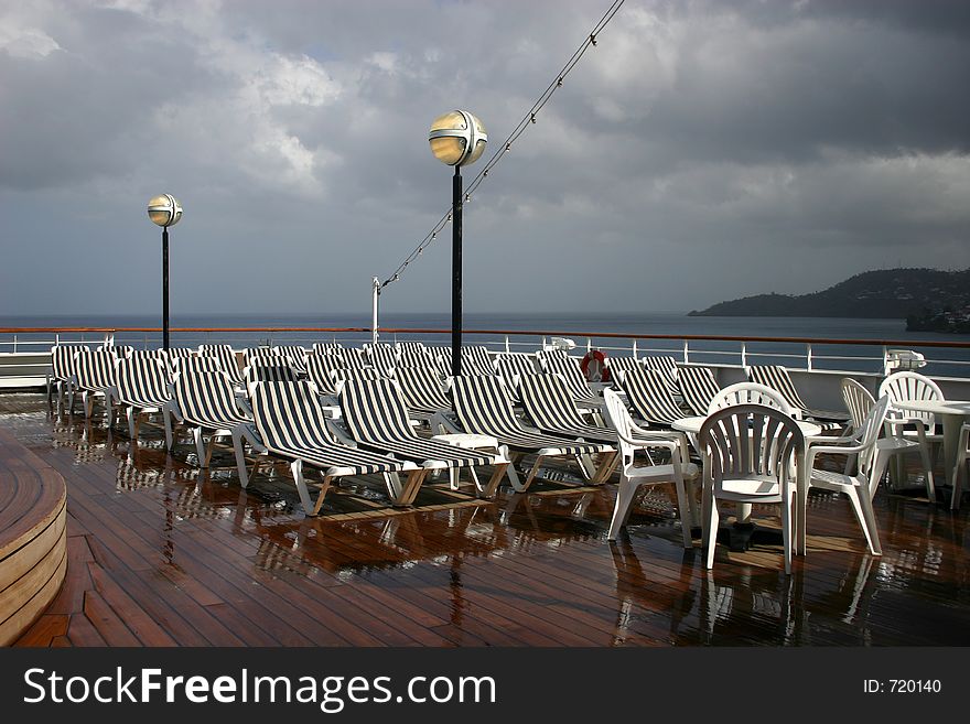 White chairs on recently washed deck of cruise ship on a cloudy morning. White chairs on recently washed deck of cruise ship on a cloudy morning