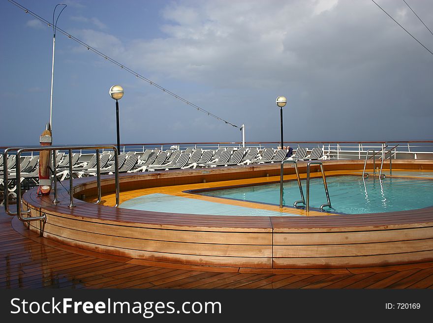 Swimming pool with wooden frame on cruise ship, with lounging chairs in background. Swimming pool with wooden frame on cruise ship, with lounging chairs in background