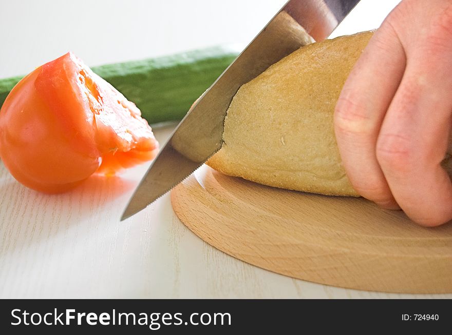 Vegetables and bread on the table in kitchen, slicing bread. Vegetables and bread on the table in kitchen, slicing bread