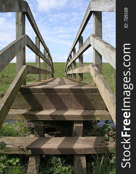 Wooden bridge leading to meadow and blue sky. Wooden bridge leading to meadow and blue sky