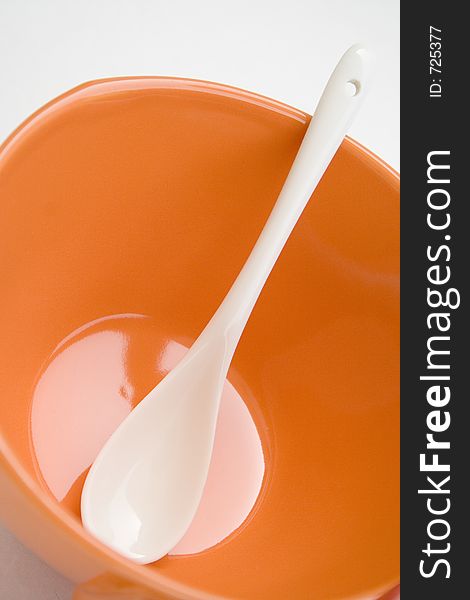 Orange cup with white spoon. Orange cup with white spoon