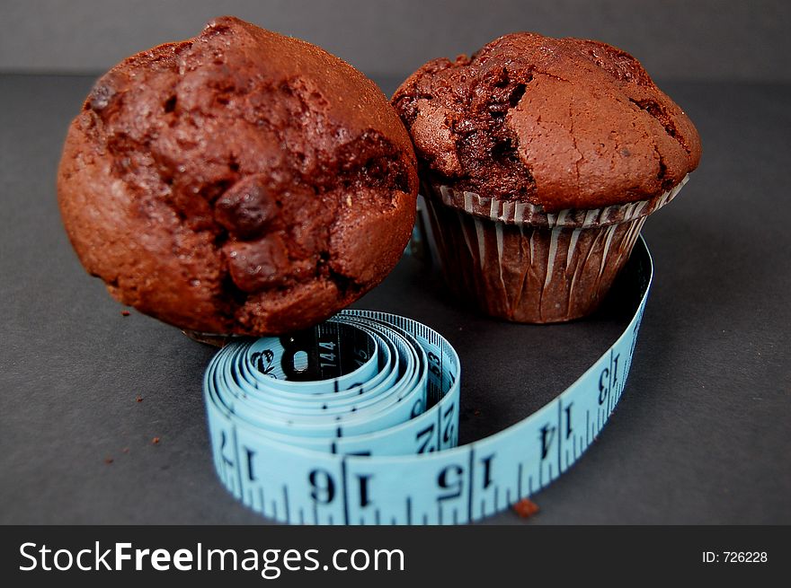 This is an image of two chocolate muffins and a measuring tape. This is a metaphor for dieting. (Please let me know where the image will be used by leaving a message in the Comments Section/See Portfolio). This is an image of two chocolate muffins and a measuring tape. This is a metaphor for dieting. (Please let me know where the image will be used by leaving a message in the Comments Section/See Portfolio)